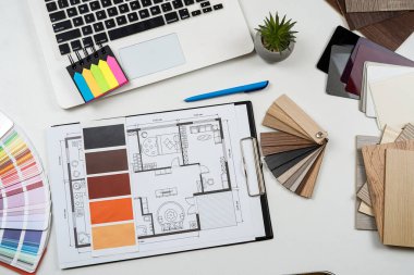 İç mimar, dizüstü bilgisayar araçları, ahşap renk örnekleri ve projenin taslaklarıyla çalışıyor. Mükemmel ev yenilemesi için tüm ekipman ve malzeme örnekleri 