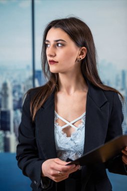 Siyah takım elbiseli bekar, güzel bir iş kadını modern ofiste elinde kağıt belgeler tutuyor. Başarılı bayan yönetici.