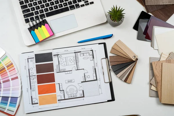 İç mimar, dizüstü bilgisayar araçları, ahşap renk örnekleri ve projenin taslaklarıyla çalışıyor. Mükemmel ev yenilemesi için tüm ekipman ve malzeme örnekleri 