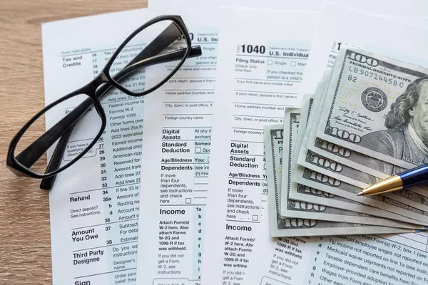 Form 1040 with pen and glasses, tax payment. Finance document