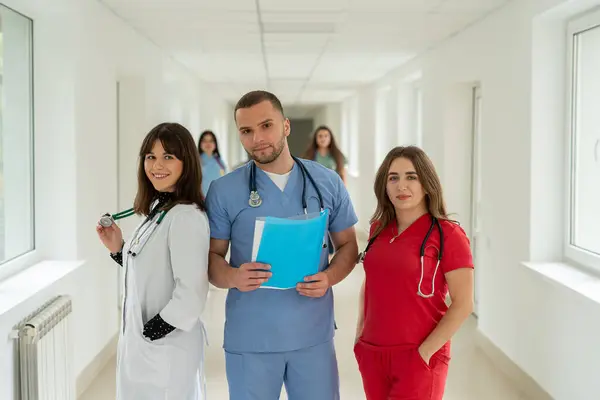 Group of medical team studetns or young doctors in uniform  in college hallway. Happy teamwork