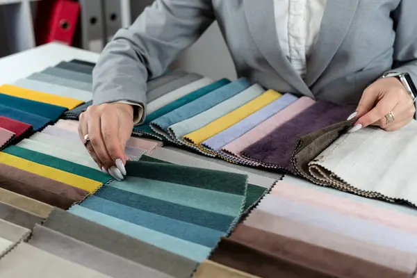close up female designer hand choosing fabric among colorful samples at office. Tissue catalog