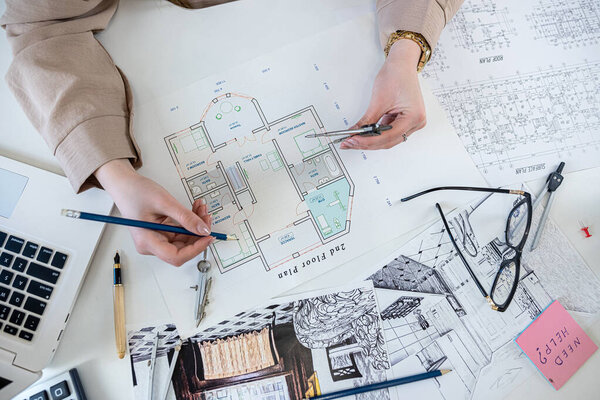 Молодая женщина-дизайнер, работающая с планом наброска синего отпечатка в офисе. Рабочее место, промышленная концепция