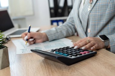 Ofisteki 1040 vergi formunu doldurmak için hesap makinesi kullanan kadın işçi. Çevrimiçi vergi ödeme