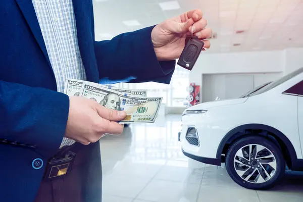 man gives dollar cash to dealer man when buying a car at modern showroom. Deal of buy or rent new auto