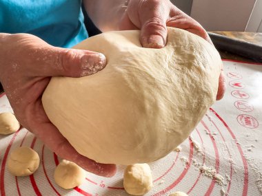 Kadın hamur yoğuruyor, ekmek yapmak için hamuru unla hazırlıyor. Ellerin hamurla çalışıyor