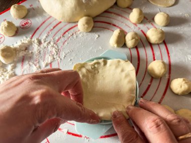 Tanınmayan kadın elleri mutfaktaki hamur ve patateslerden hamur köfteleri yontuyor. Ev yapımı çiğ yemek.