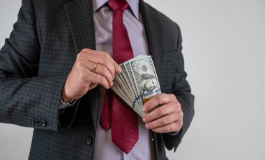 Genç iş adamı, elindeki dolarları gri ve finans sayısına izole ederek gösteriyor.