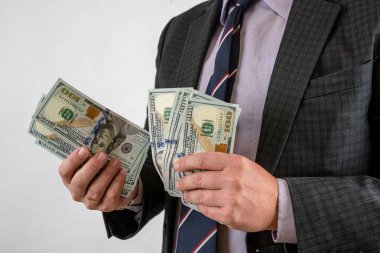 Takım elbiseli adam parayı sayıyor ve biz dolarları gri üzerine izole ediyoruz. Finans kavramı