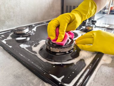 Mutfaktaki bez ve beyaz köpük gaz sobasıyla kadın el temizliğini kapat. Oda servisi kavramı