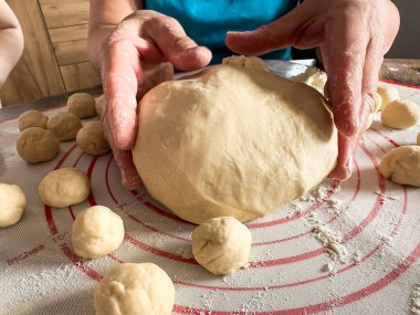 Kadın hamur yoğuruyor, ekmek yapmak için hamuru unla hazırlıyor. Ellerin hamurla çalışıyor
