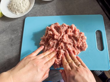 Kadın eli metal kasede kıyma yapar ya da mutfakta hamburger yapar. Pişmemiş yemek.