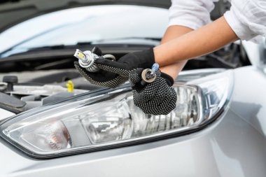  Bir adam arabanın ampulünü değiştiriyor, yolcu arabasının farında lamba tamir ediyor.