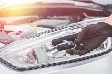 Arabada yenisi için ampulü tut. Auro tamir konsepti. Bir adam araba tamir ediyor.