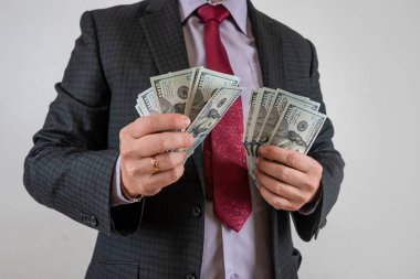 Takım elbiseli adam parayı sayıyor ve biz dolarları gri üzerine izole ediyoruz. Finans kavramı