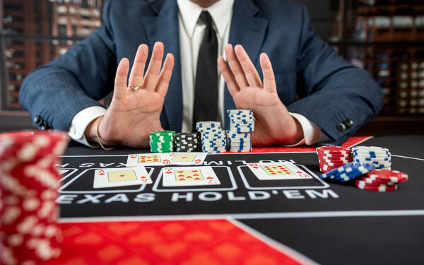 Gambler man hands pushing chips and going all-in in poker game at casino. Gambling entertainment concept 