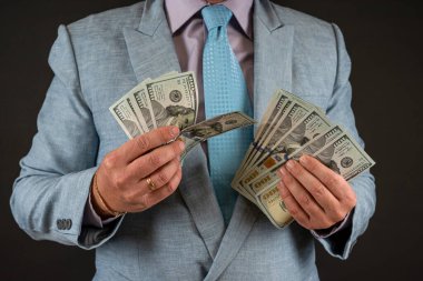 İş adamı takım elbise giyer ve bize siyah üzerine izole edilmiş dolar para banknotlarını gösterir. Finans kavramı