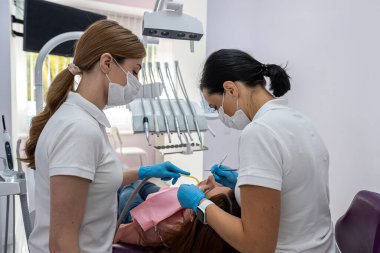 young female patient being examined and treated by a female dentist and an assistant in a dental clinic. treatment of the oral cavity