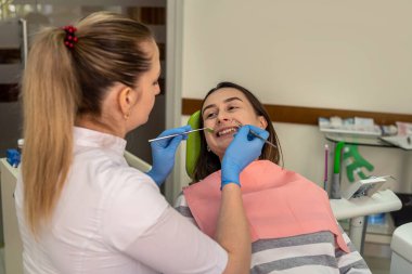 Avrupalı genç kadın önleyici tedbirler alıyor ve dişçide dişlerini muayene ediyor. Stomatoloji dolabını ziyaret eden bir kadın. Sağlıklı yaşam tarzı