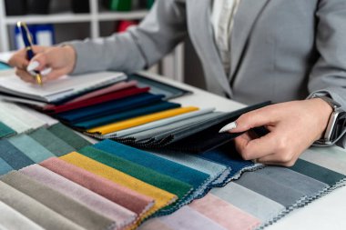  Yeni kanepe kataloğunda kadın eli, kumaşların renklerini ve desenlerini gösterir. Masadaki renkli doku