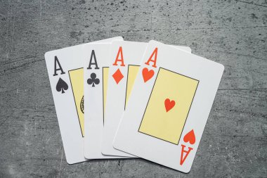Gri masada kağıt oynayan dört as. Kumar konsepti