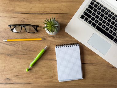 Dizüstü bilgisayarı olan bir iş yeri, ofis masasında boş defter ofis malzemeleri. Yaratıcı bir geçmiş. Düz yatıyordu