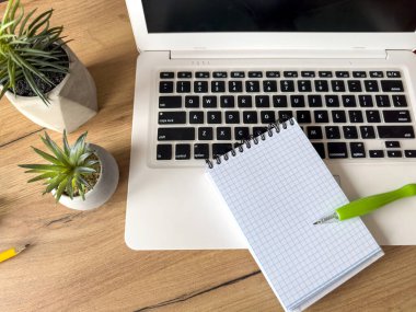 Dizüstü bilgisayarı olan bir iş yeri, ofis masasında boş defter ofis malzemeleri. Yaratıcı bir geçmiş. Düz yatıyordu