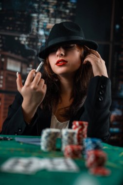 image of a young sexy woman playing poker with a cigarette and smoke coming out of it. poker in the casino. woman with cards