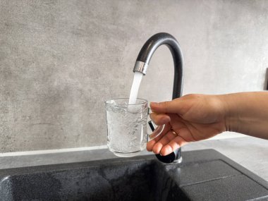 Mutfak musluğundaki temiz suyu bardağa dolduran eli kapat. Sağlıklı yaşam tarzı