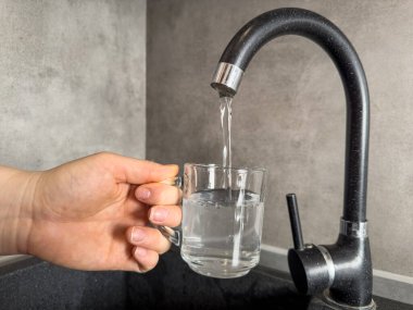 Mutfak musluğundaki temiz suyu bardağa dolduran eli kapat. Sağlıklı yaşam tarzı