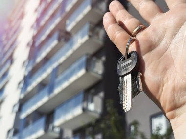 Kadının elinde çok katlı bir yerleşim yerine karşı anahtar var. Konut satın alma ve kiralama kavramı 