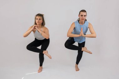 Spor giyim esneme antrenmanındaki iki genç kadın stüdyoda izole edilmiş. Yoga ya da pilates egzersizi