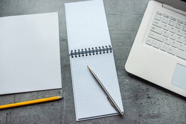 Boş bir defter kalemi olan ofis masası dizüstü bilgisayarı, uzak bir işte çalışma yeri. Düz yatış, üst görünüm