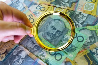 Avustralya parasıyla el ele tutuşan büyüteç. Konept kaydediliyor