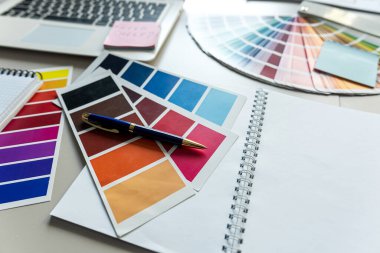 Notlar için dizüstü bilgisayarı ve not defteri olan masaüstü renk kataloğu, yaratıcı işyeri