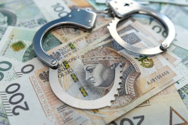 Zloty pln paralı kelepçeler masanın üstünde. Ekonomik suç kavramı