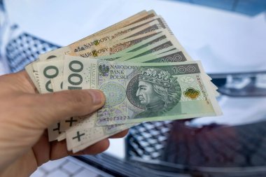 PIn Zl Zloty, galeride yeni arabanın yanındaki erkek elinin üzerine para döker. Alış veriş kredisi ve araba konsepti