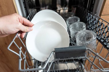 Erkek eli, bulaşık makinesinden temiz bulaşık takımı alıyor. Mutfak aletleri, yaşam tarzı.