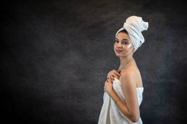 Beyaz havluyla, şişkinlik ve kırışıklıklar için göz bandı yapıştıran tatmin olmuş bir kadın. Cilt bakımı, sağlıklı yaşam biçimi konsepti