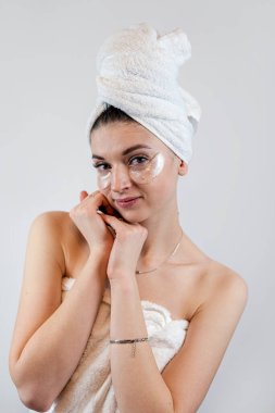 Beyaza izole edilmiş hidrojel göz bantları olan güzel bir kadın. Kaplıca yüz tedavisi kavramı 