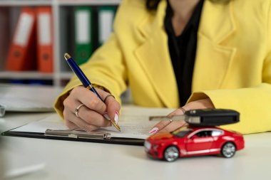 Ofiste yeni bir araba almak ya da kiralamak için başvuru formu imzalayan bir kadın ajan. Otomatik sigorta