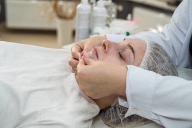 Masör terapist yüz masajı prosedürünü yeniliyor. Kozmetikçi tarafından cilt bakımı. Dermatoloji kavramı