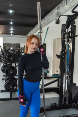 Spor salonunda duran beyaz tenli güçlü kadın eğitmen portresi. Spor salonunda idman.