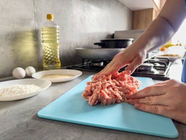 Dişi eller çiğ yemek pişirmek için kıymalı eti ön bant olarak karıştırıyor. Yemek pişirme konsepti
