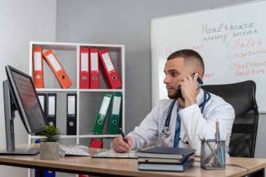 Genç doktor ya da pratisyen hekim klinikteki hasta dosyalarında çalışıyor. Hastalık tedavisi