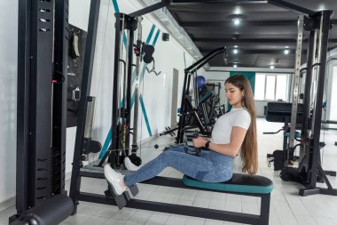 Kafkasyalı sporcu kadın spor salonunda egzersiz makinesiyle egzersiz yapıyor. Herkes için spor.