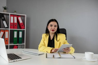 Genç beyaz iş kadını dizüstü bilgisayarda çalışıyor ve ofiste notlar alıyor. İşyeri