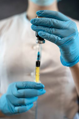 Koruyucu giysiler içinde kadın doktor elinde şırınga, tıbbi sağlık konsepti