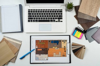 İç mimar, dizüstü bilgisayar araçları, ahşap renk örnekleri ve projenin taslaklarıyla çalışıyor. Mükemmel ev yenilemesi için tüm ekipman ve malzeme örnekleri 