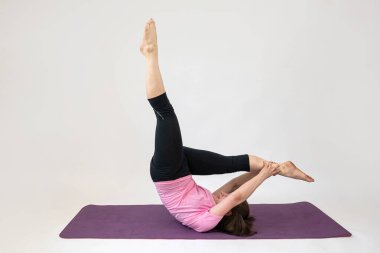 Sportif kadın yoga minderi üzerinde egzersiz yapıyor. Beyazlar üzerinde izole edilmiş beyaz bir minder. Yoga yaşam tarzı eğitimi